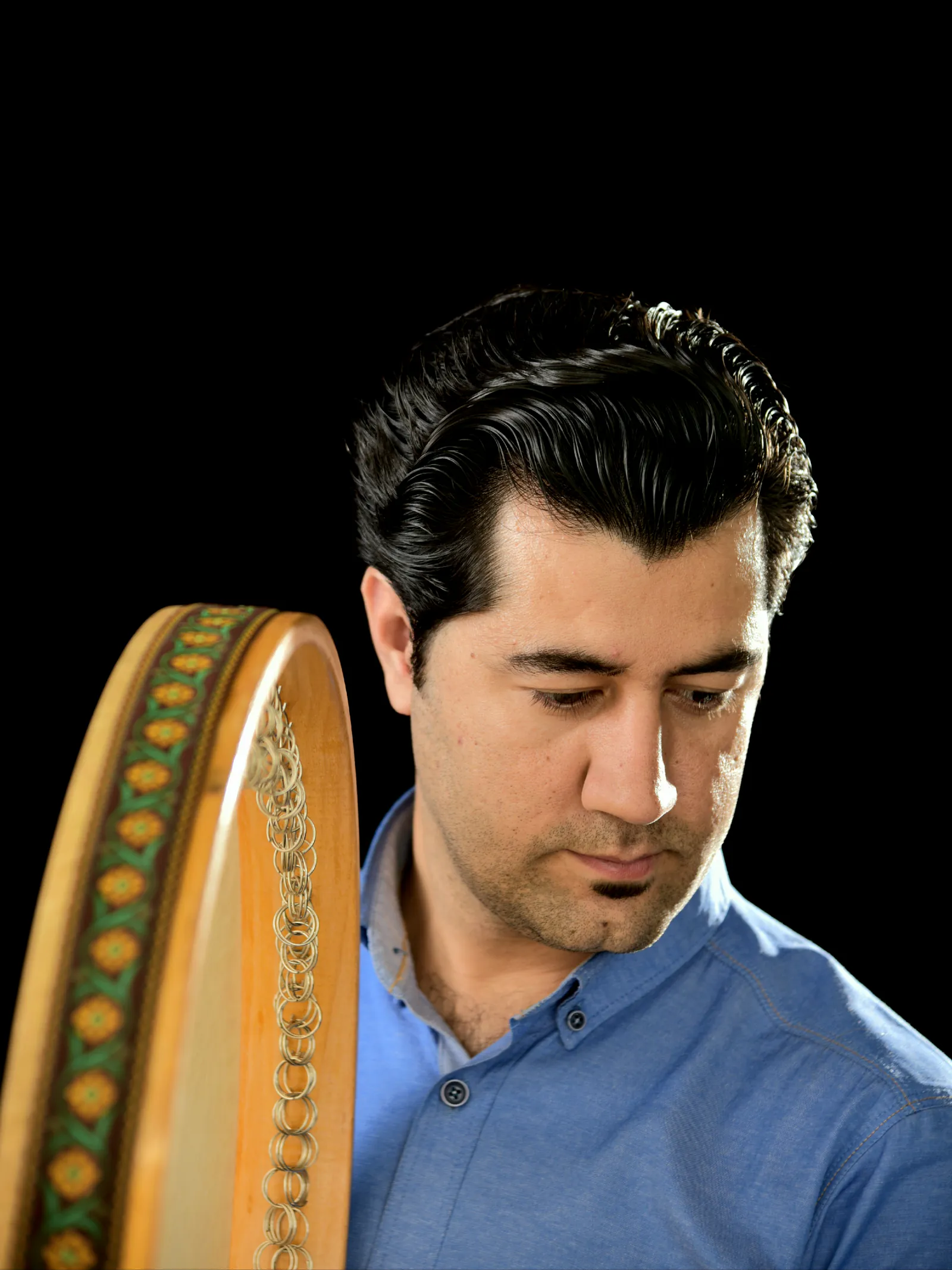 Farid Zandi with a Daf against a dark studio background.