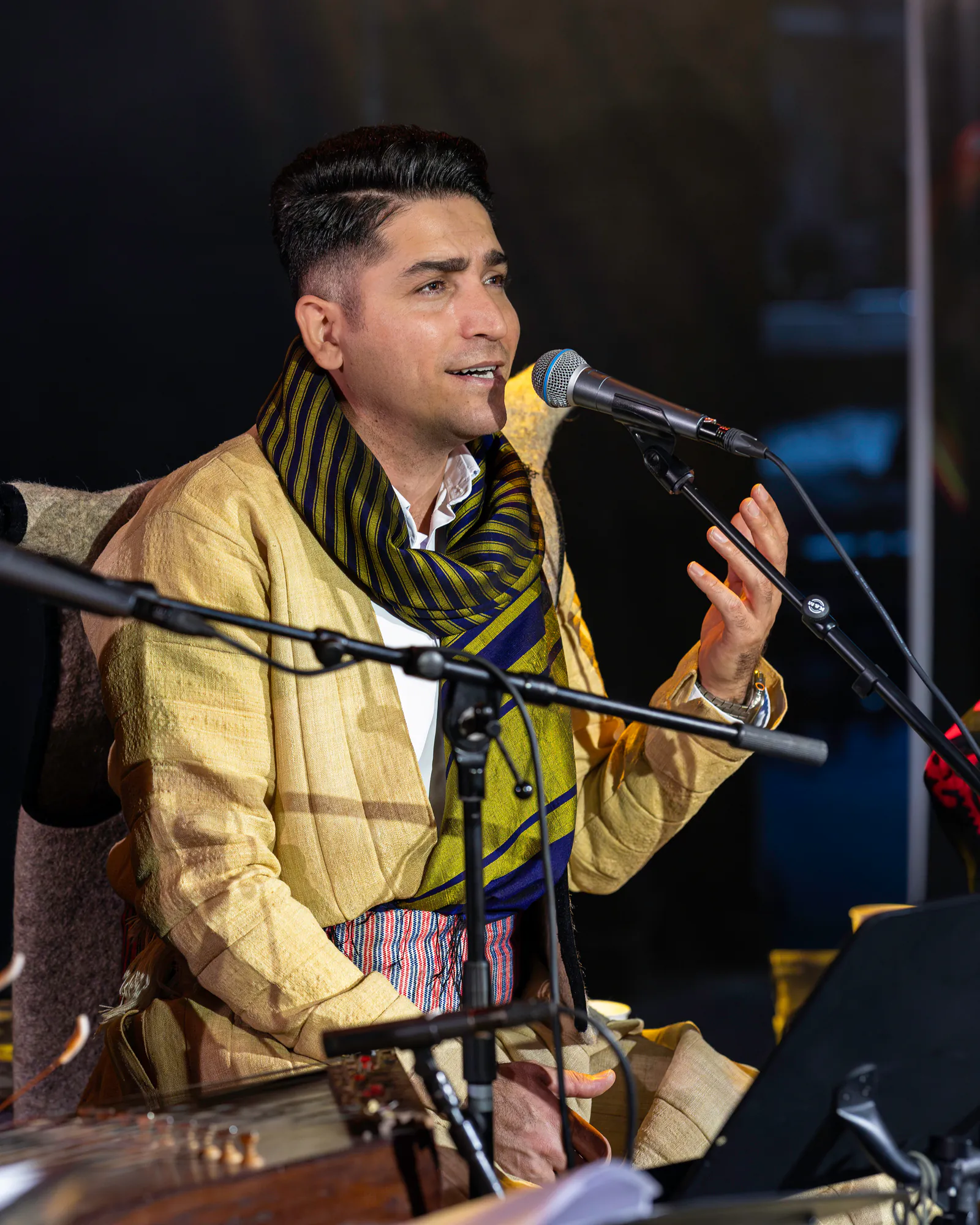 Farzad Mehdi Nia singing into a microphone during a live performance.