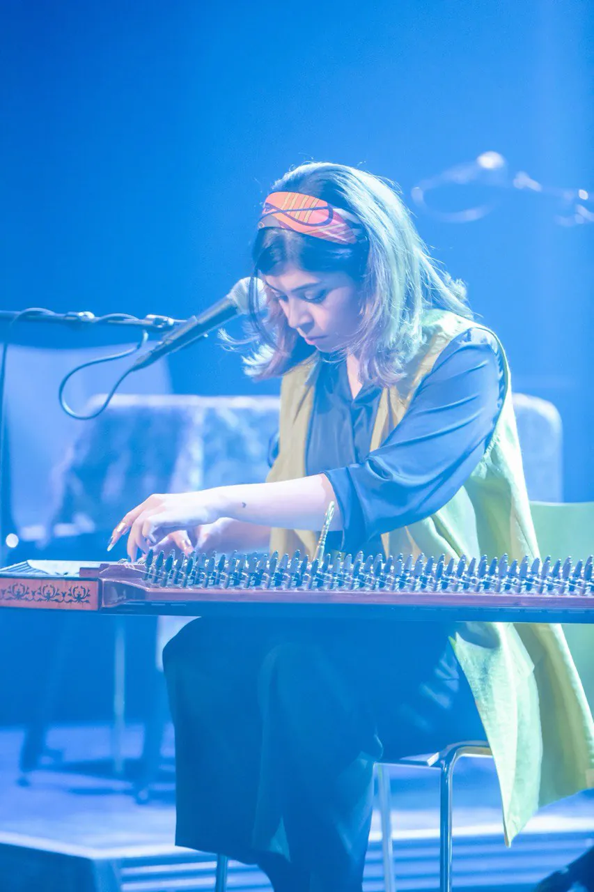 Sara Majidinejad playing Qanun under blue stage lighting.