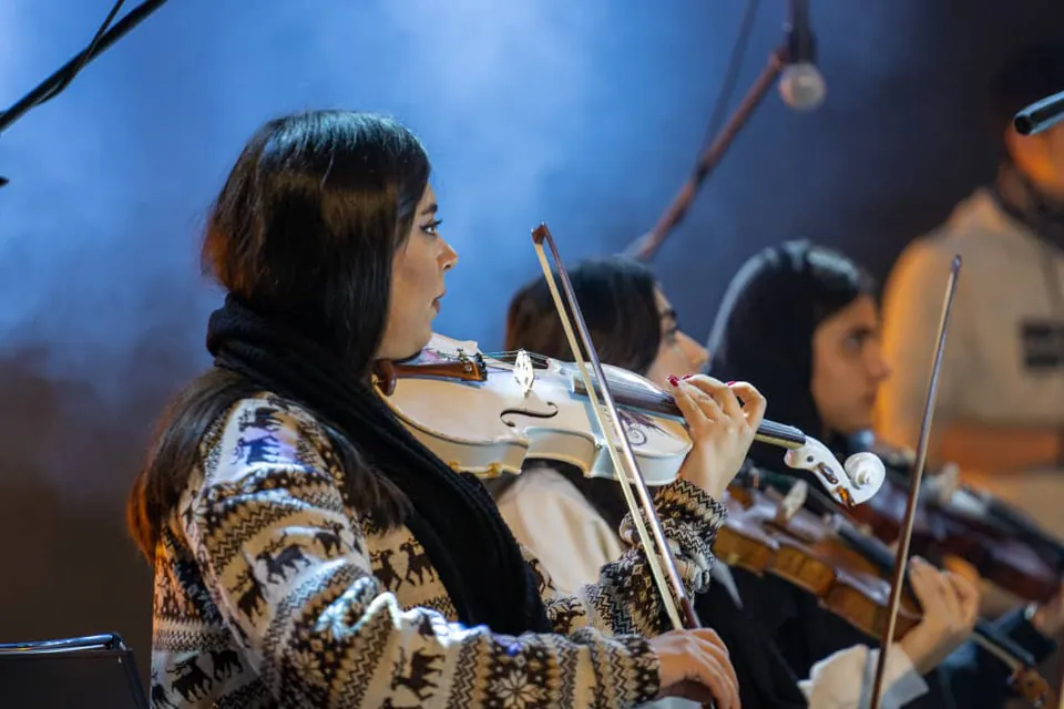 Shno Sharifzadeh playing violin with an ensemble.